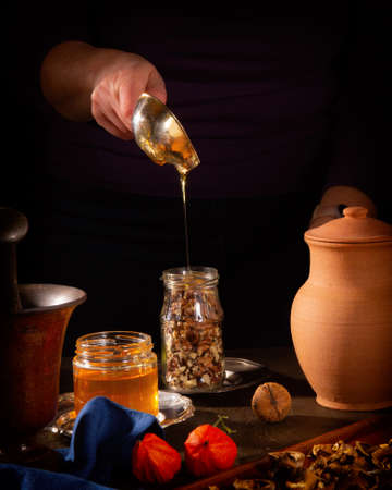 Cooking a delicious dessert - walnuts in honey. Filling the jar with honeyの写真素材