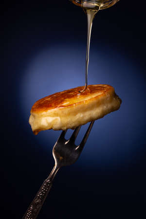Fresh fried pancakes on a metal fork, dark blue backgroundの写真素材
