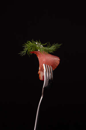 Pieces of cold smoked meat strung on a metal forkの写真素材