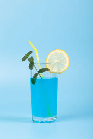 Glass with refreshing drink and fruits on blue backgroundの写真素材