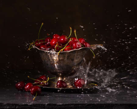 Ripe red cherries in a vase with splashing waterの写真素材