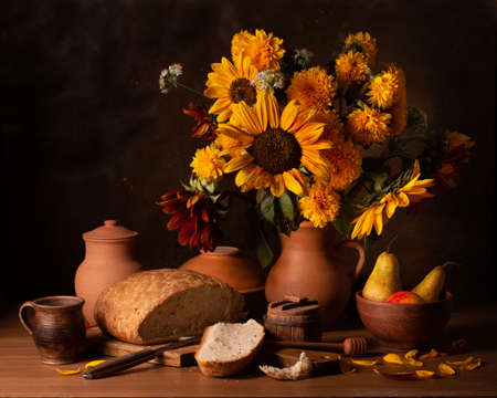 Classic still life with a bouquet of autumn flowers and breadの写真素材