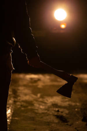 Man stands on the road at night and holds an axの写真素材