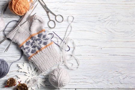 Flat lay of knitting and winter accessories on white wooden background