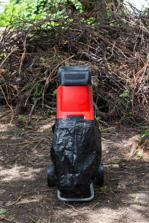 Garden chipper, electric shredder mulcher against the background of a pile of dry branchesの写真素材