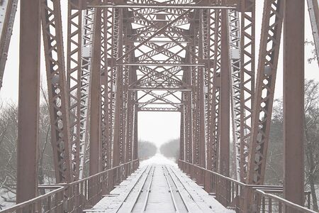 Winter landscape. Metall red bridge over the frozen river