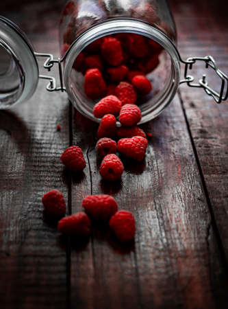fresh ripe raspberries from the jar are scattered on the table