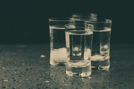 A glass of vodka on the black table, selective focus and toned imageの写真素材