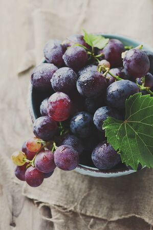 Red sweet grape on the wooden table, selective focus and toned imageの写真素材
