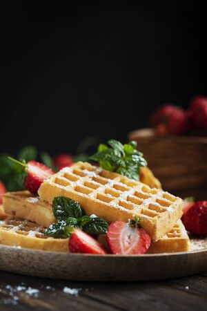 Homemade sweet waffle with powder sugar, strawberry and mint, rustic style and selective focusの写真素材