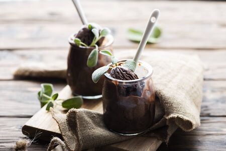 Sweet chocolate ice cream with sage on the wooden table, selective focus