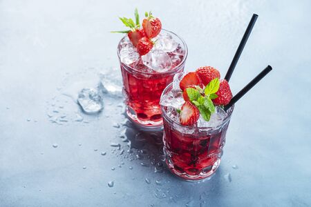 Red cocktail with ice and mint. Bar concept. Strawberry mojito with mint and ice on the blue background, selective focus imageの写真素材