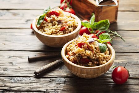 Vegetaian rice with onion, tomato and eggplant in the wooden bowl, rustic style and selective focusの写真素材