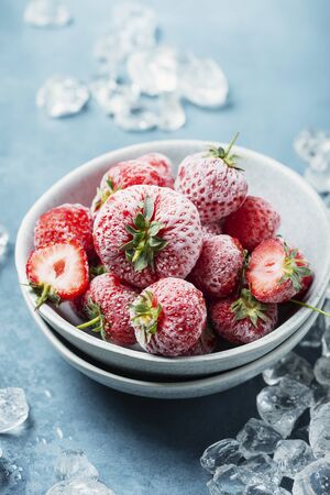 Frozen strawberry with crystals of ice on the blue background, selective focus imageの写真素材
