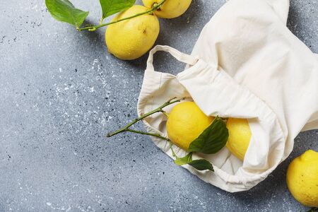 Concept of a biological healthy food and zero waste. Fresh biological lemons with green leaves in a cotton shopping bag. Top view image with a copy spaceの写真素材
