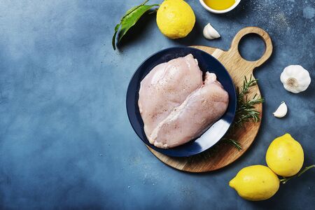 Healthy eating concept. Ingredients for cooking chicken breast with lemons, rosemary and pepper, top view image with copy spaceの写真素材