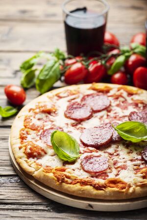 concept of Italian pizza with tomato and salami, rustic stlye and selective focus imageの写真素材
