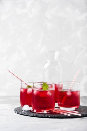 Red alcoholic coctail with ice and mint on a stone background, selective focusの写真素材