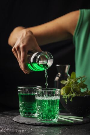 Alcoholic green cocktail with mint and lime on the black background, selective focusの写真素材