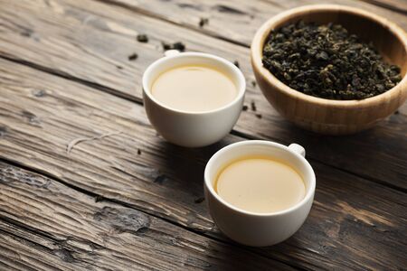 Two cups with hot green tea and raw tea on the wooden table, selective focus imageの写真素材