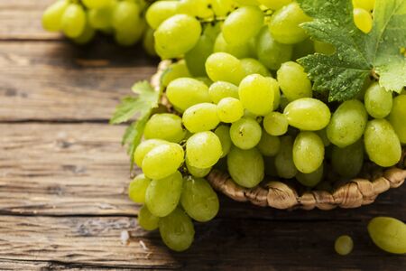 Sweet yellow grape with leaves on the rustic wooden table, selective focusの写真素材