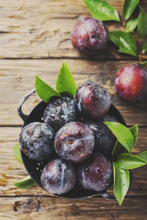 Sweet red plums on the wooden rustic table, selective focus and toned imageの写真素材