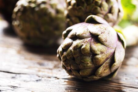 Raw italian artichoke on the wooden table, selective focus imageの写真素材
