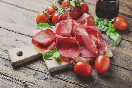 Italian antipasto with bresaola and red wine, selective focus and toned image