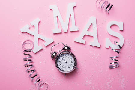 Christmas card with letters and clock on the pink background. Christmas concept, top down view