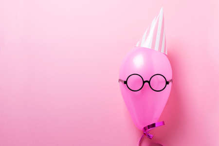 Party concept with pink ballon, party hat and looking glass. Top down view in pink backgroundの写真素材