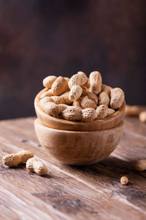Roasted peanuts in wooden bowl on dark background, selective focus imageの写真素材