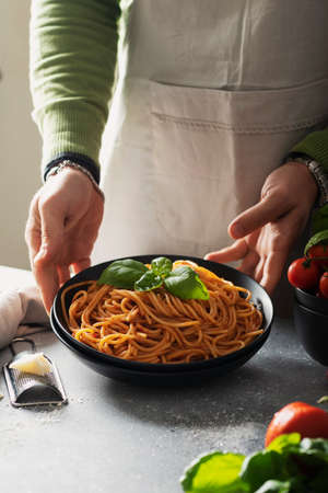 Restaurant concept. Man cooking italian spaghetti with tomato and basil, selective focus imageの写真素材