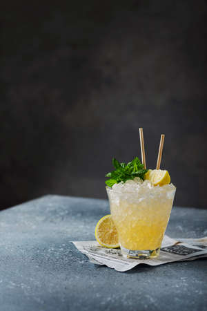 Bar concept: Yellow cocktail with lemon, mint and crushed ice on the black background, selective focus imageの写真素材