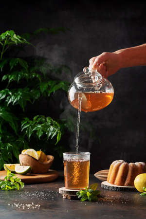 Woman hand pourung a hot black tea on the black background, selective focus imageの写真素材