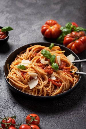 Traditional Italian pasta with tomato sauce, basil and cheese on the black background, top down view with copy spaceの写真素材