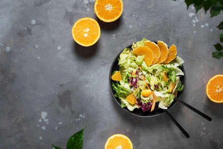 Concept of vegan food with green salad and oranges, top down view with copy space