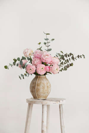 Spring bouquet of peonies and ranunculus in a beige vase, selective focus image