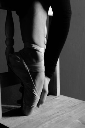 View of a ballerina stretching over a chairの写真素材
