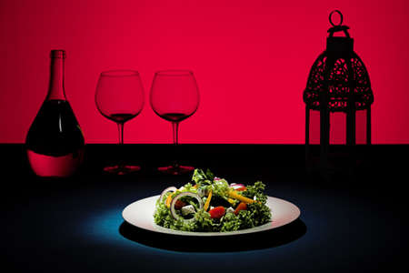 Salad plate with red background and glasses in silhouetteの写真素材