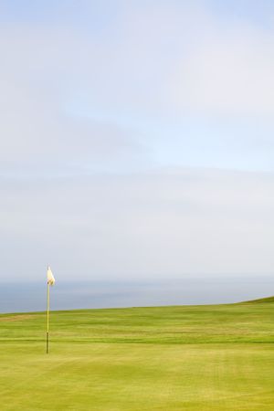Green on a golf course with a red flag on a yellow flag pole.の写真素材