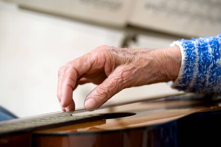 Closeup of an elderly woman playing the guitar.の写真素材