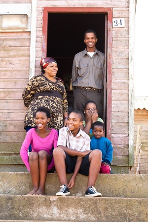 Cheerful black family on the steps infront of their rural house.の写真素材