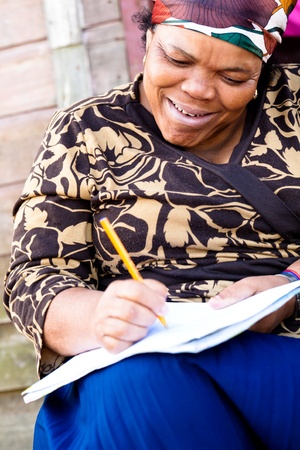 Black woman filling out a form while sitting on steps.の写真素材