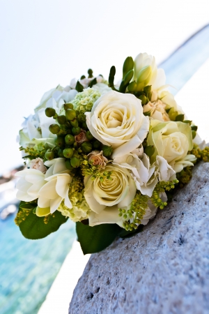 A white rose bouquet laying on a rock by the ocean.の写真素材