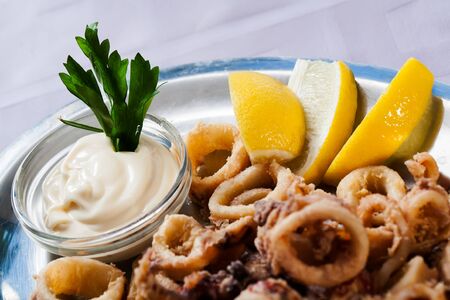 Thick calamari rings served with sauce and lemons の写真素材