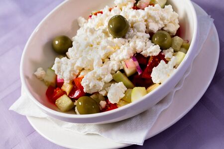 Feta cheese salad with olives, apples and tomatoes.の写真素材