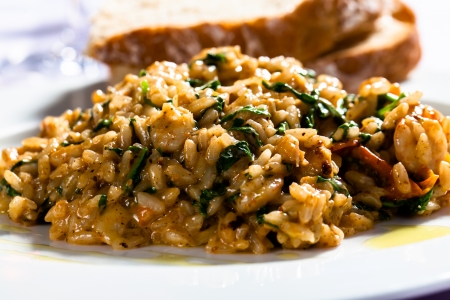 Risotto with spinach and bacon served with white bread.の写真素材