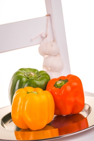 Green, Orange and red peppers in the studio with three garlics の写真素材