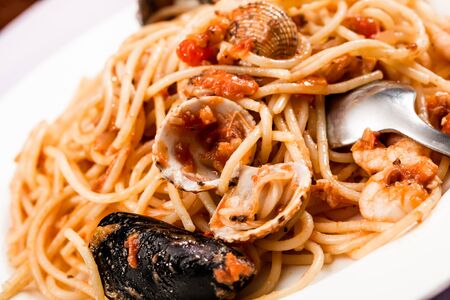 Mussels and noodles is served in a bowl with tomato sauce の写真素材