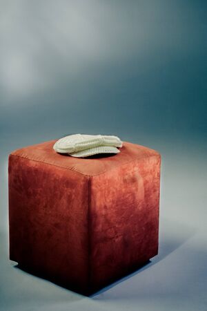 A white wool cap laying on a orange stool for art photography.の写真素材